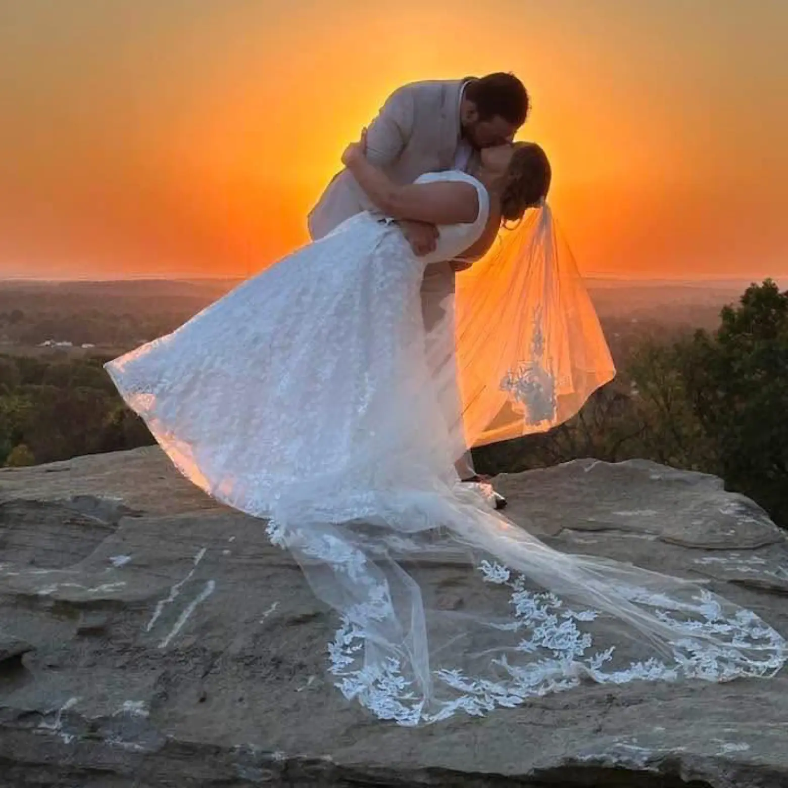 A couple in a golden-hour dip on the LIKAZOO grounds, the bride's dress catching the last warm light.