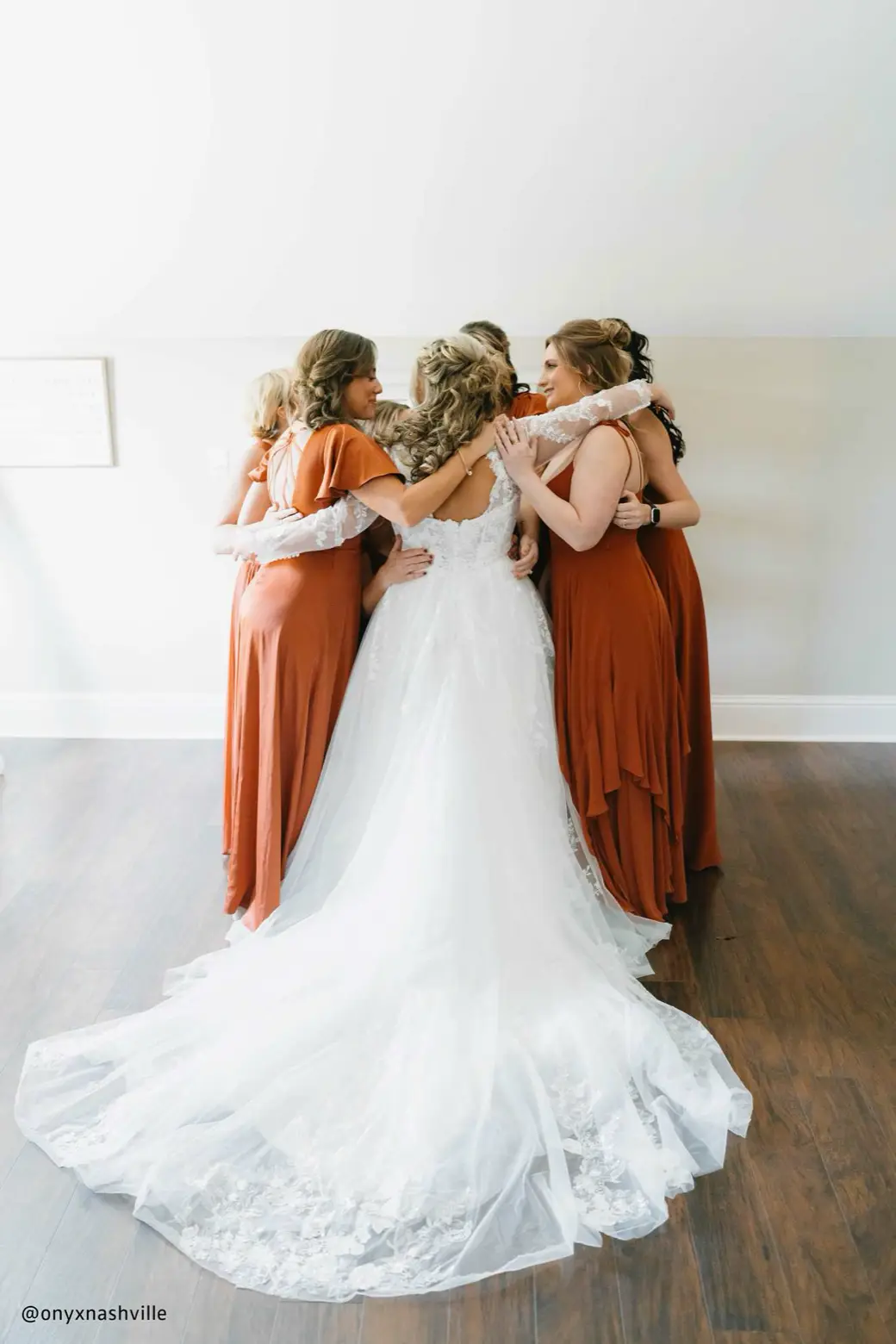 A bride embracing her bridesmaids in a close, joyful hug.
